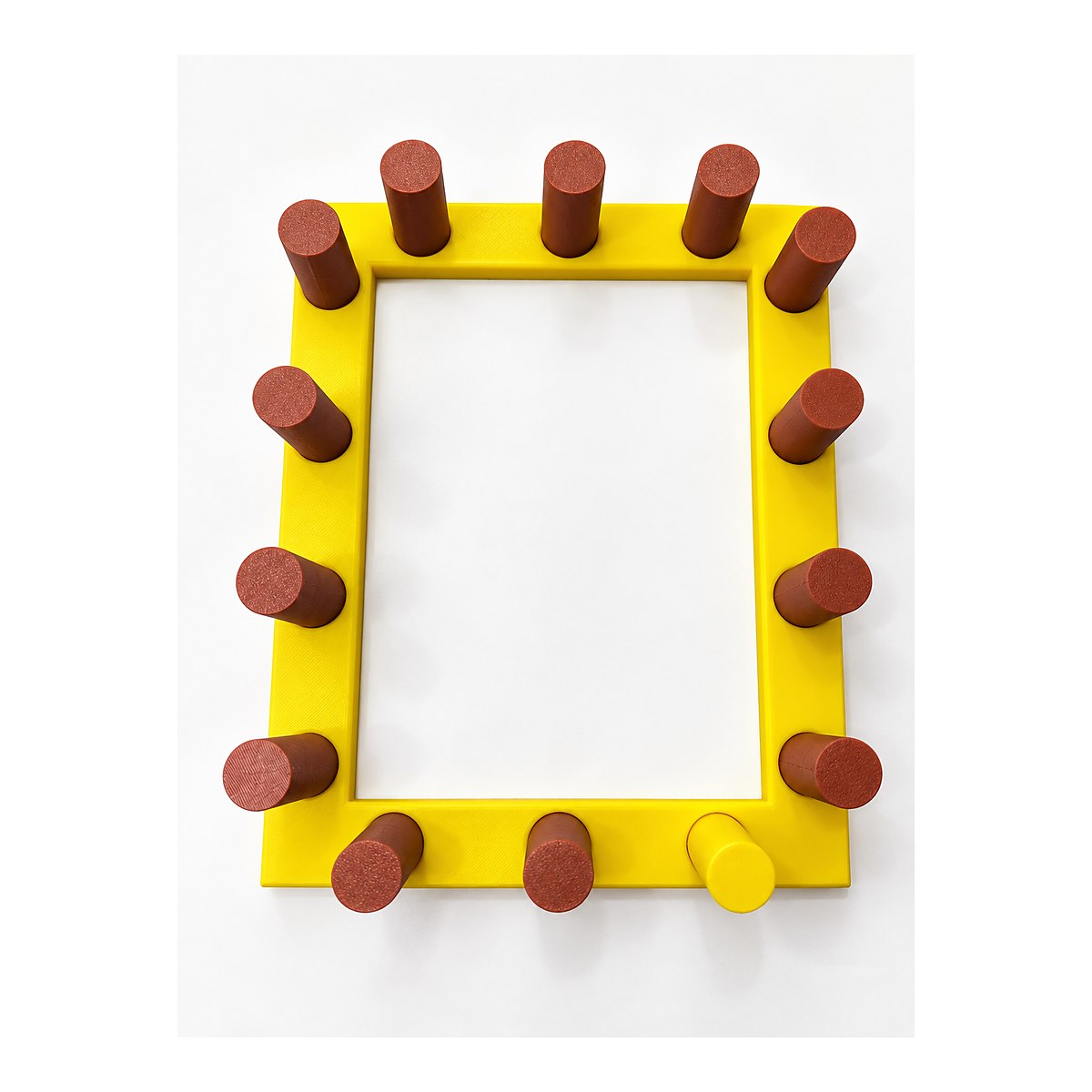 Urdidor de mesa impreso en 3D, marco amarillo con doce clavijas cafés, visto desde arriba